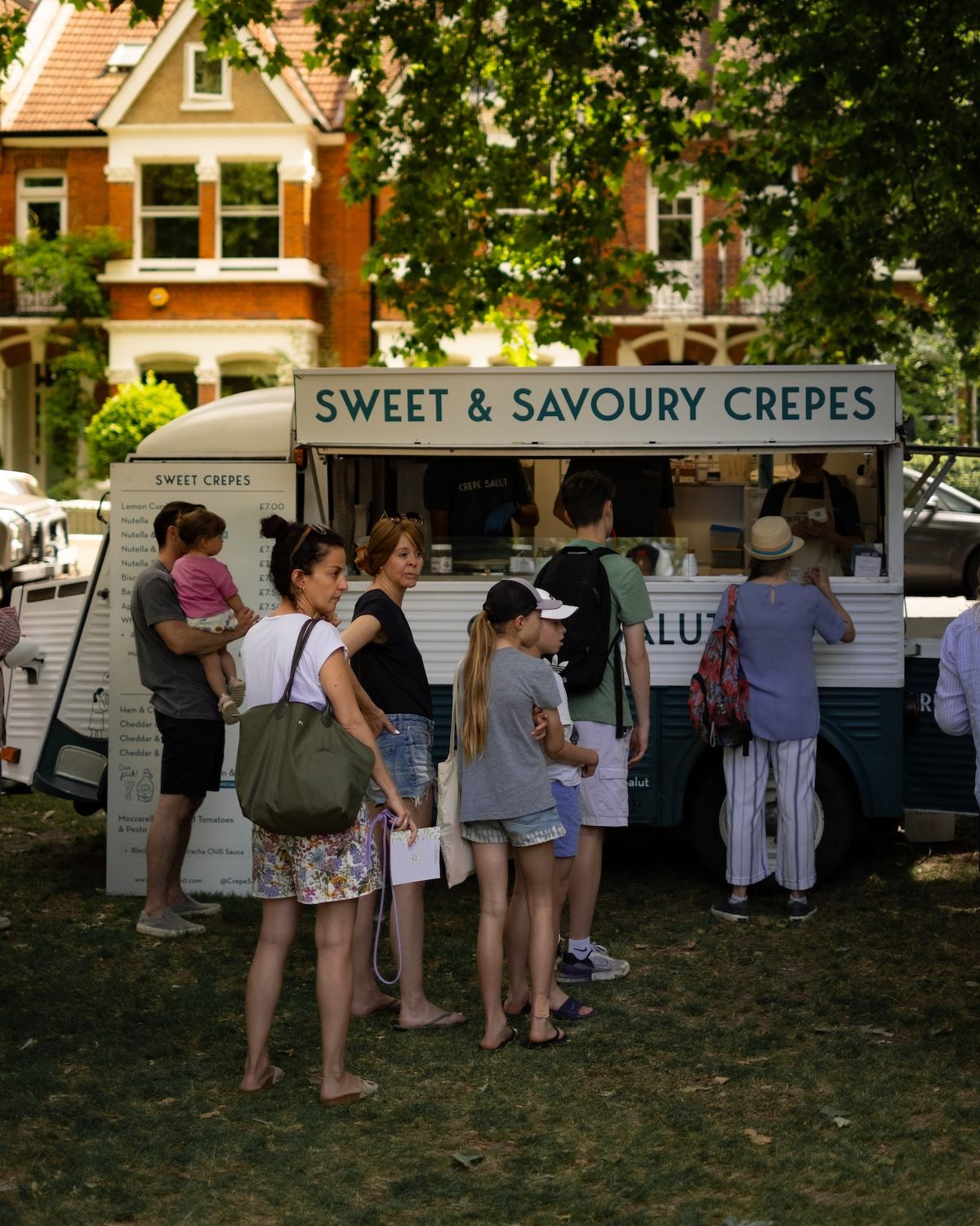 Customers queuing at the crepe van in a leafy park