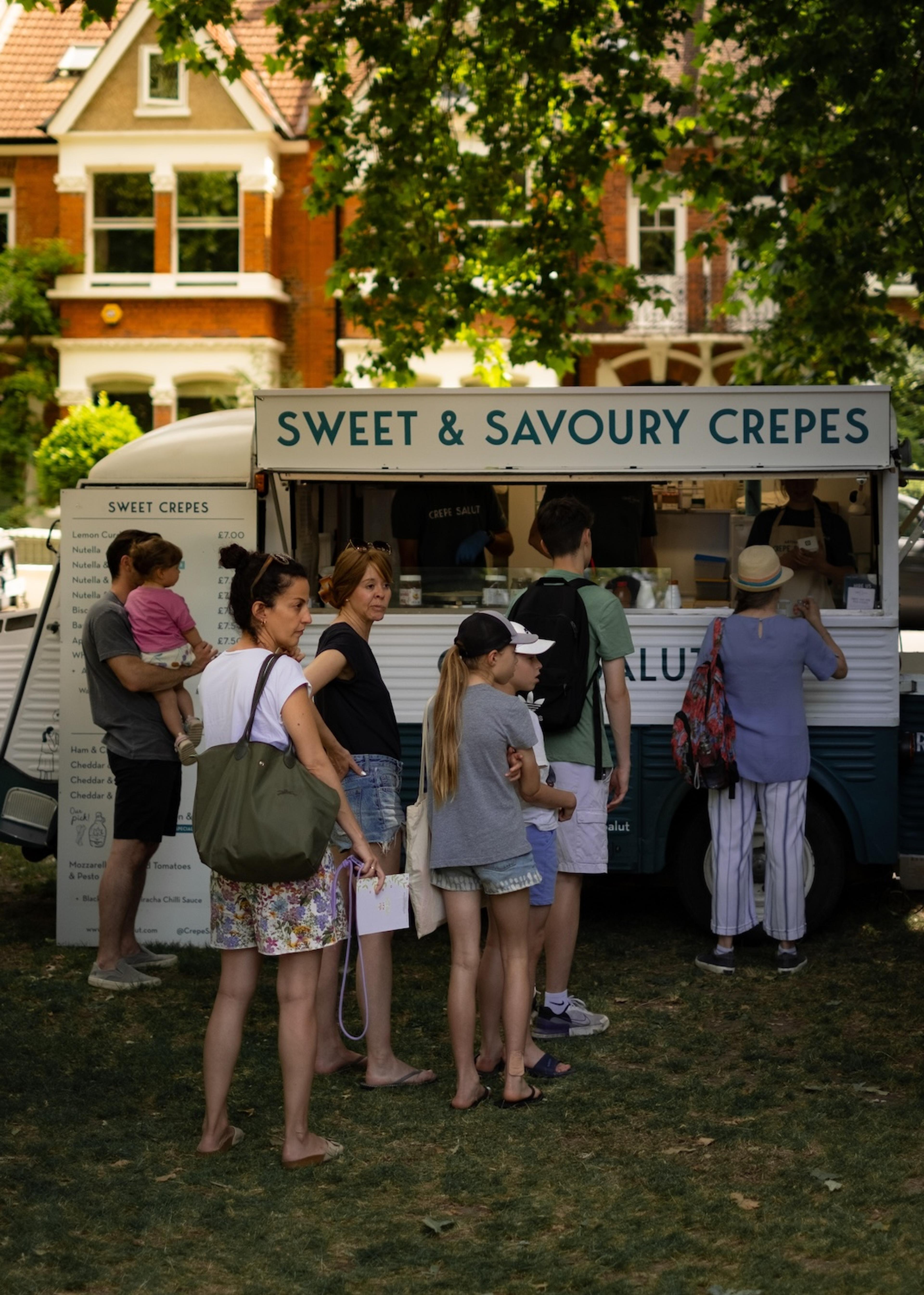 Customers queuing at the crepe van in a leafy park