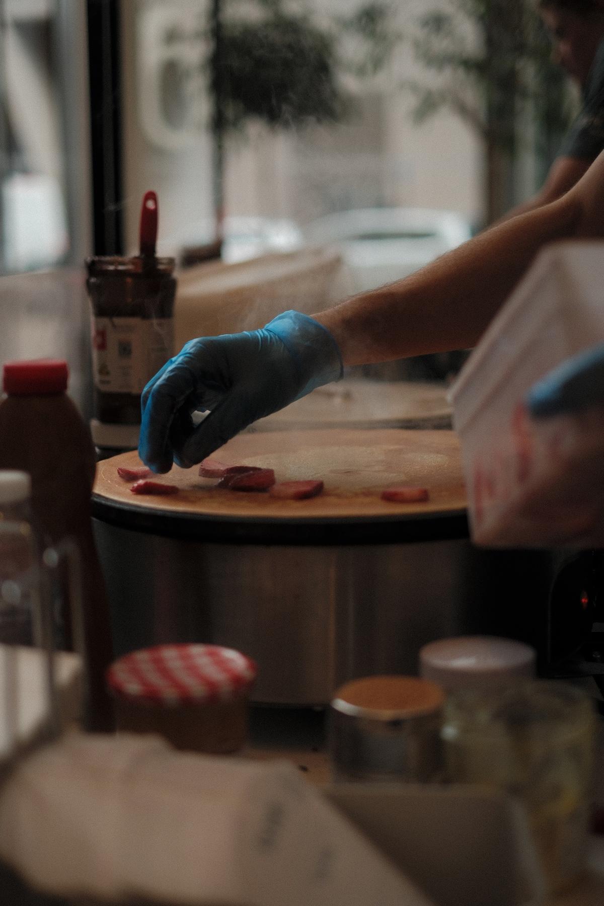 Adding strawberries to a crepe on the griddle