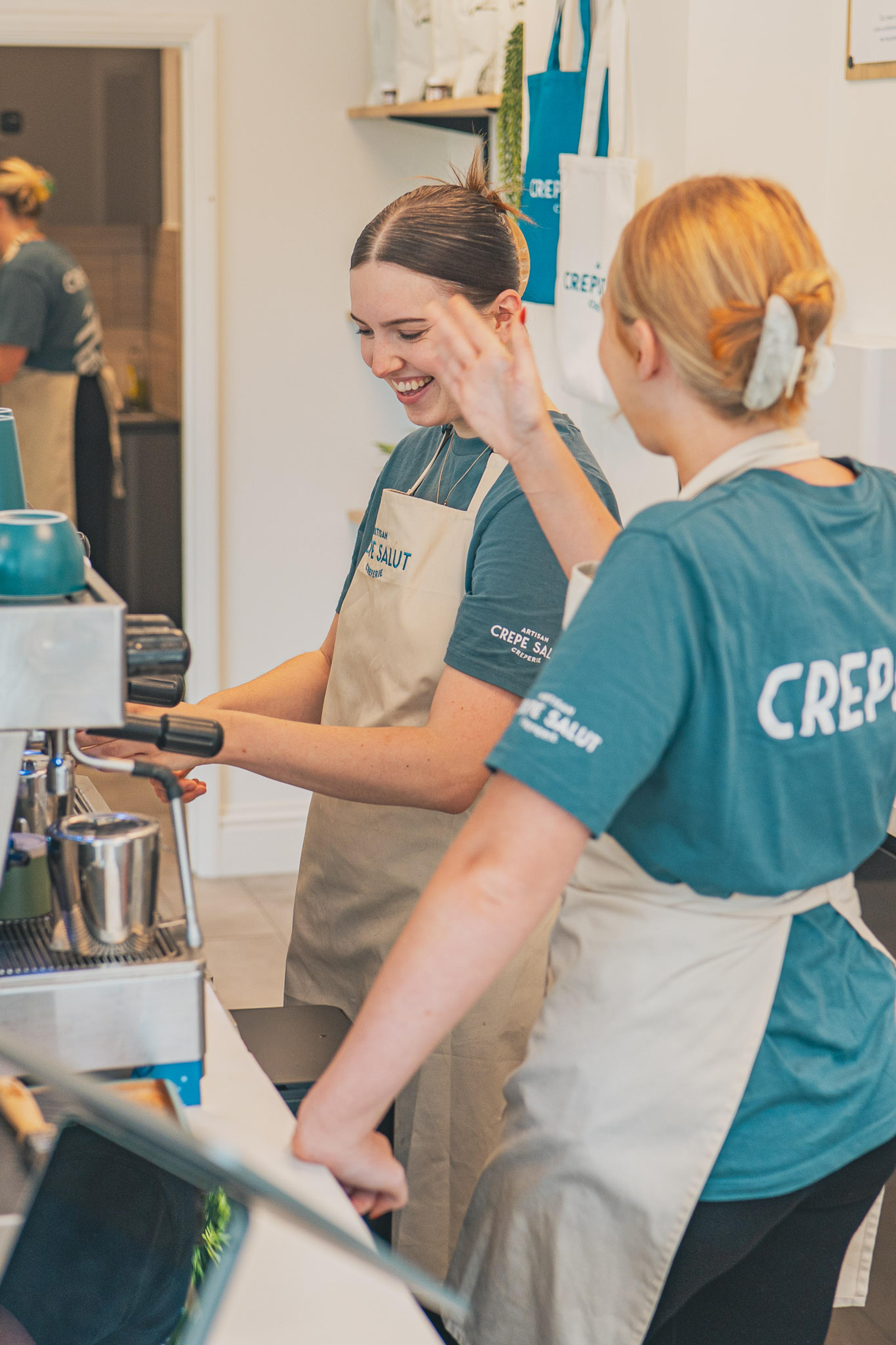 Two team members laughing together at the coffee machine