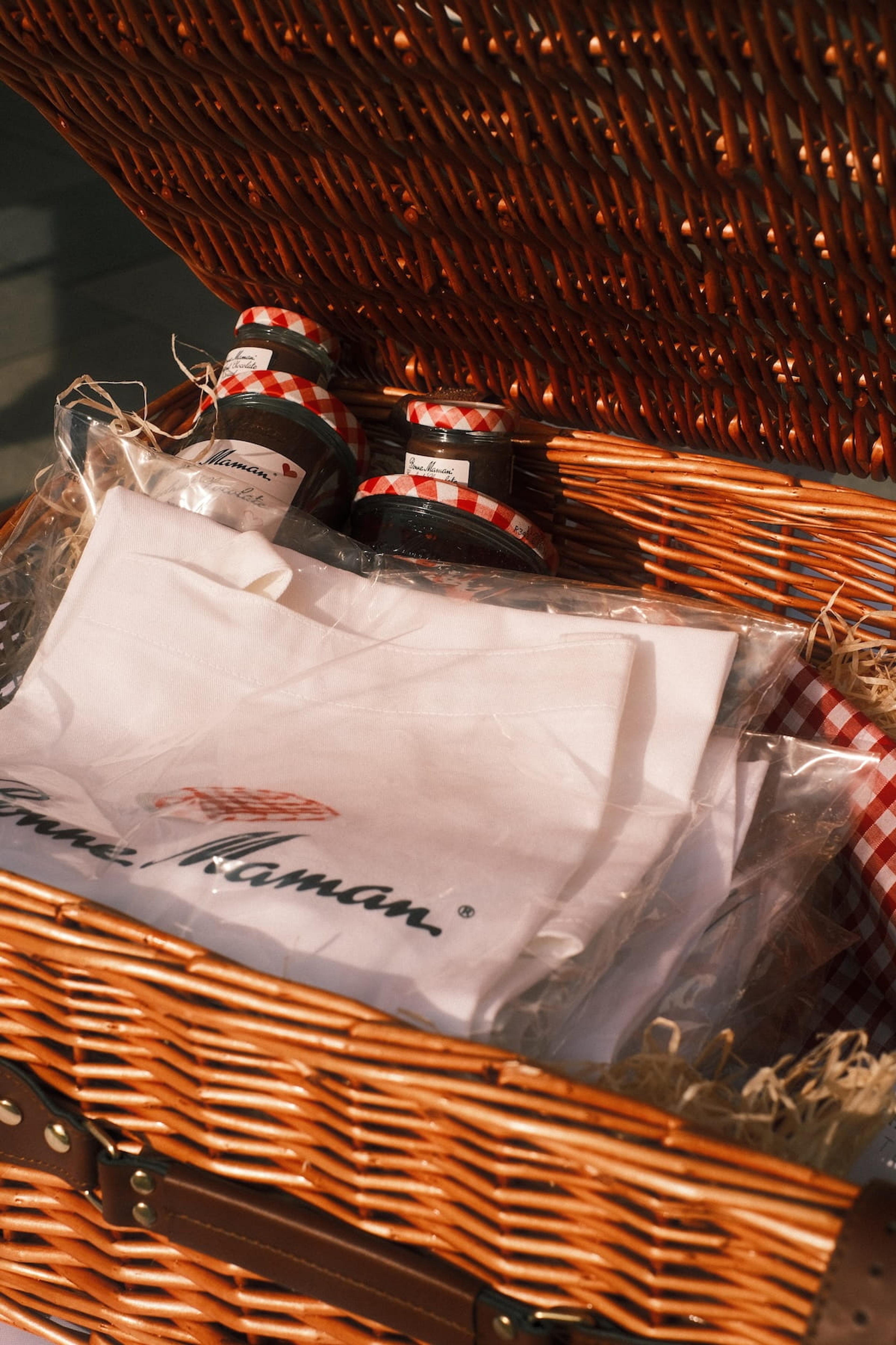 A wicker hamper of Bonne Maman jars and branded aprons