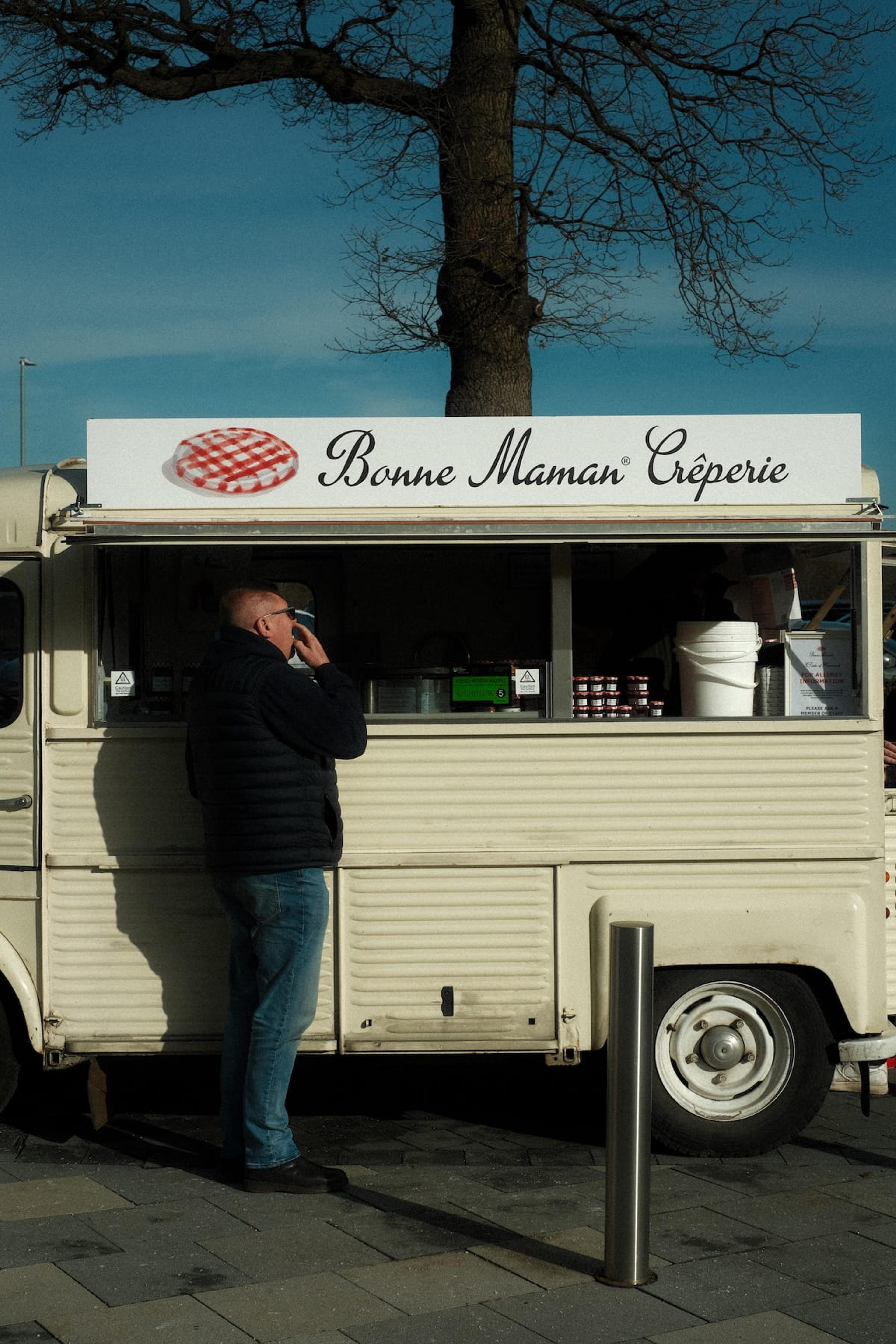 A customer being served at the hatch of the Bonne Maman Creperie van
