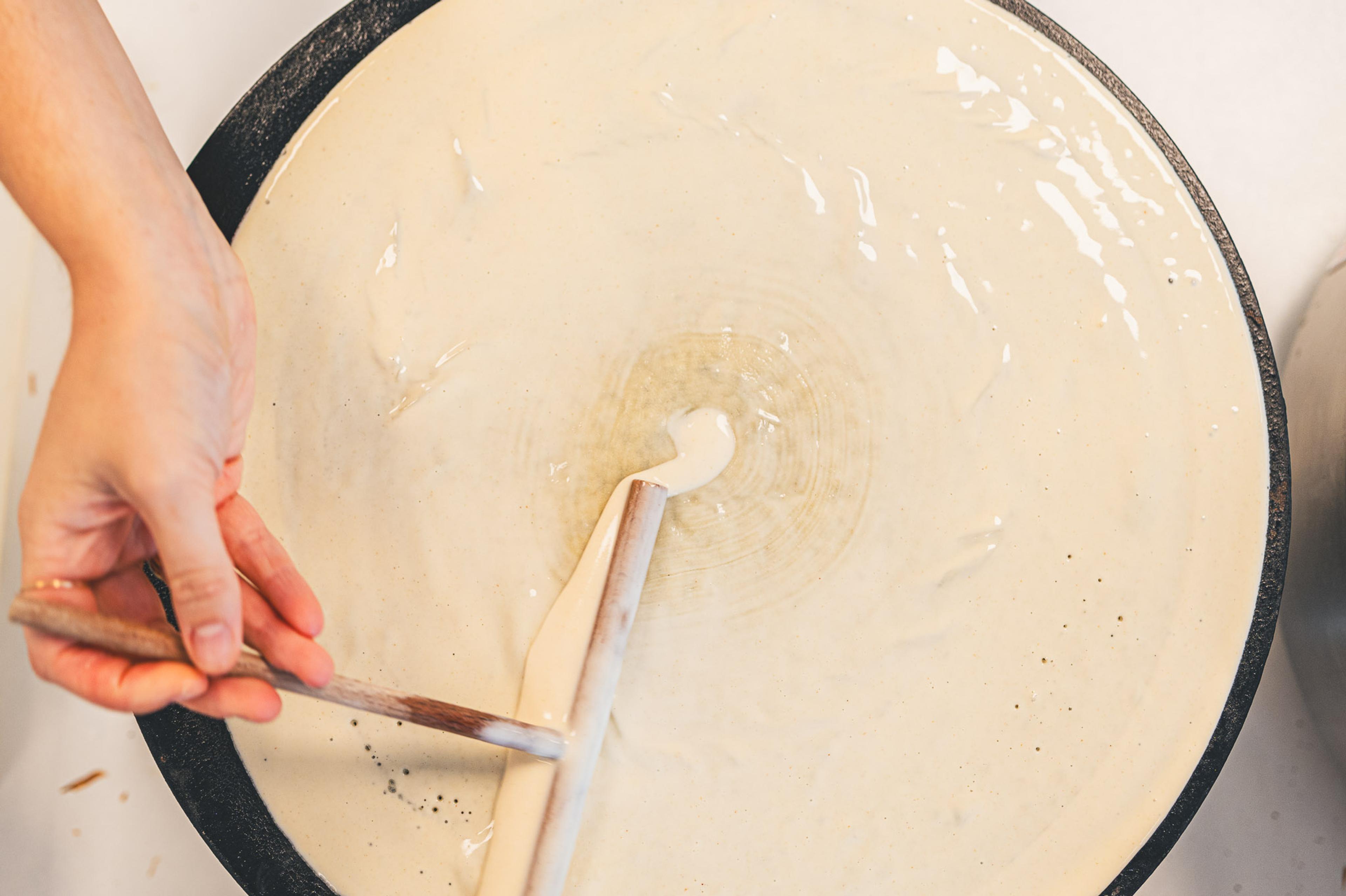 Spreading crepe batter on the griddle with a wooden spreader