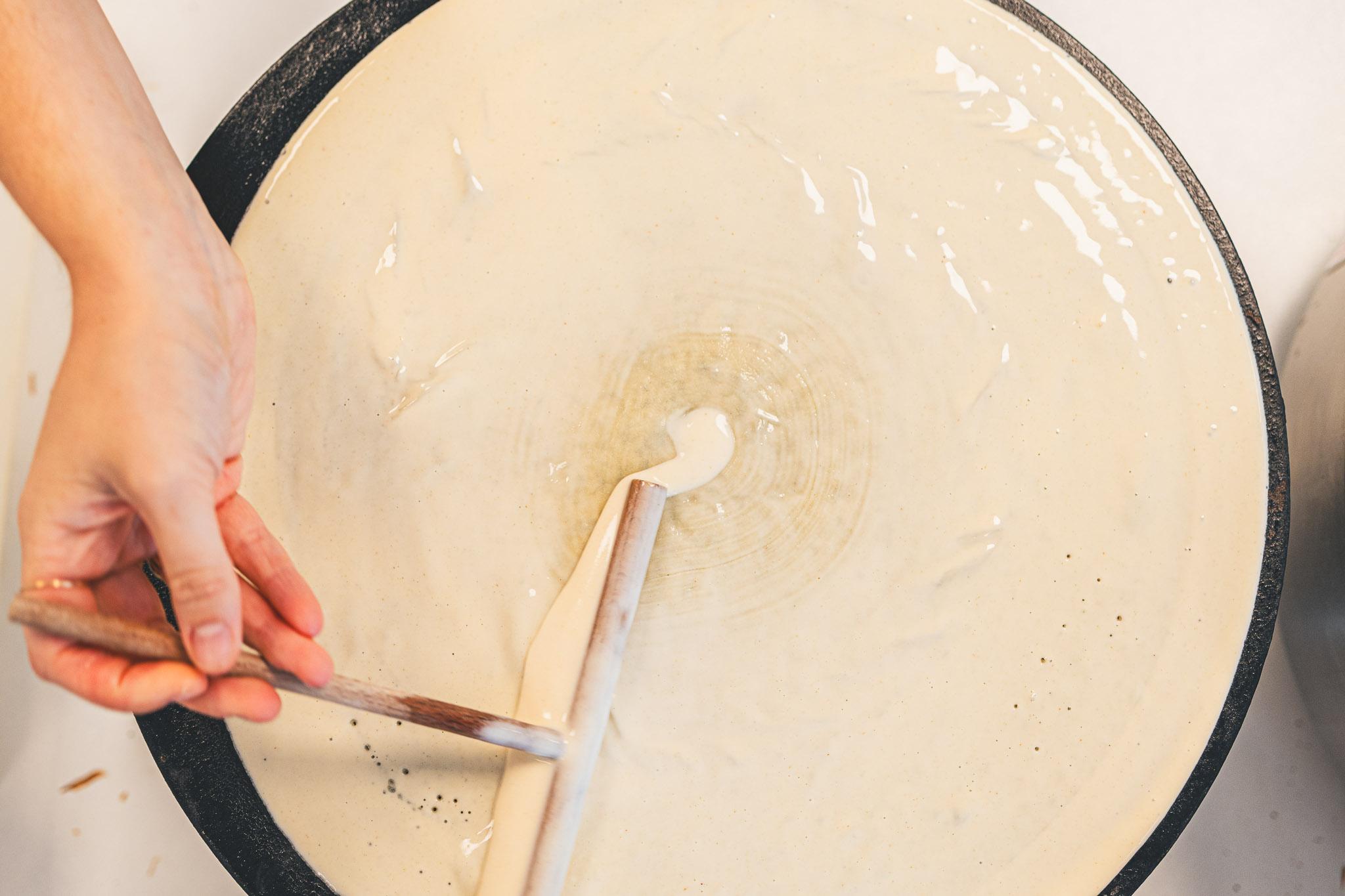 Spreading crepe batter on the griddle with a wooden spreader