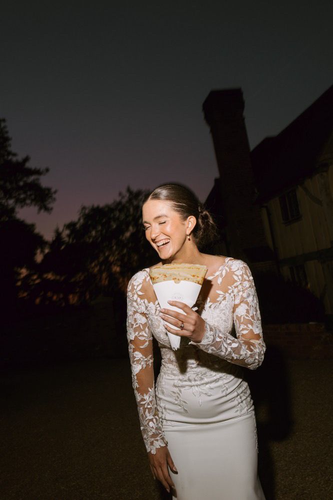 A bride holding a crepe outside the van at night