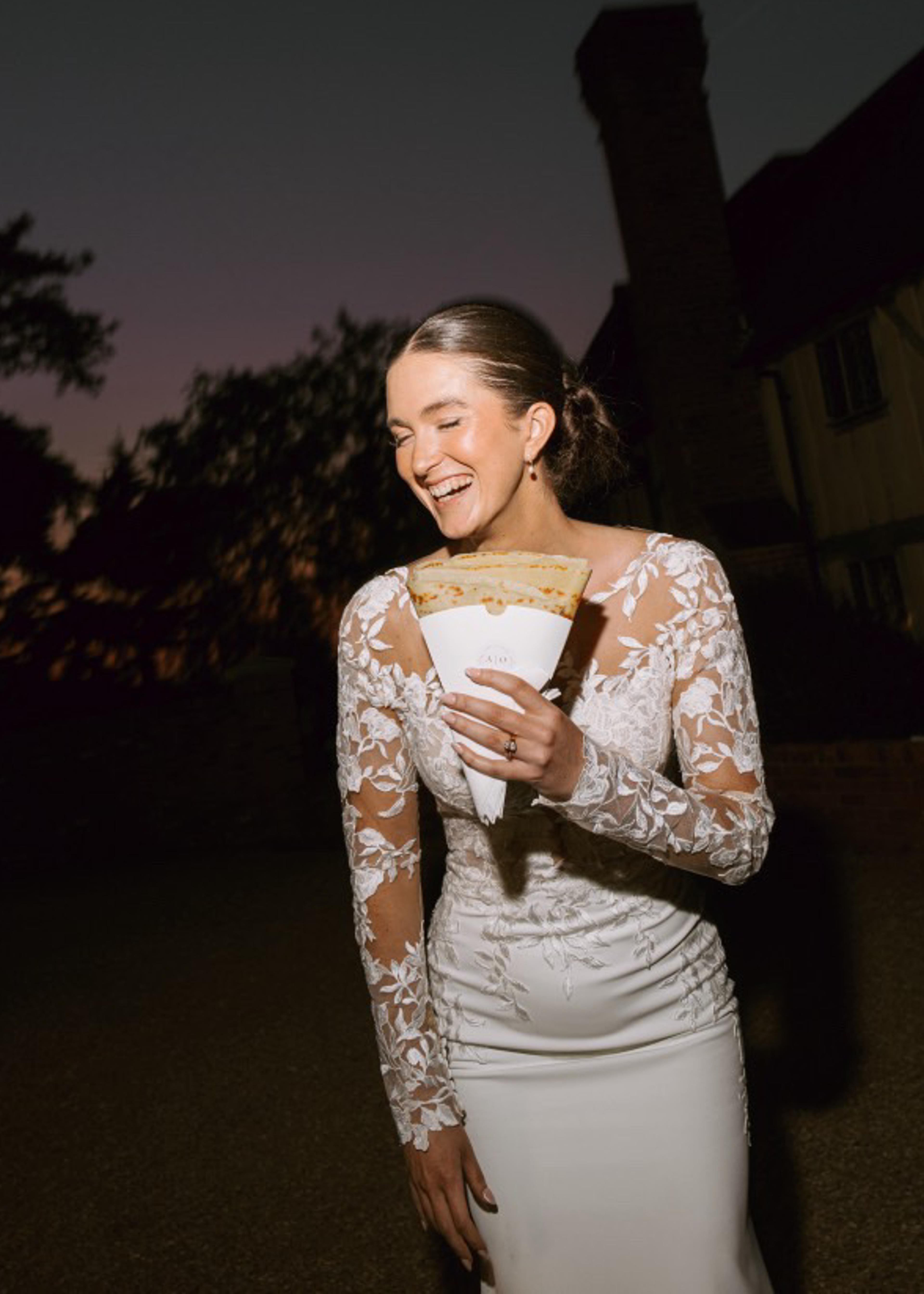 A bride holding a crepe outside the van at night