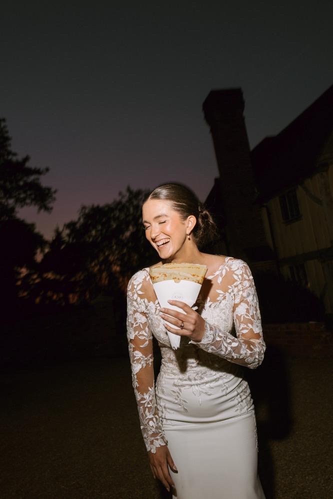 A bride holding a crepe outside the van at night