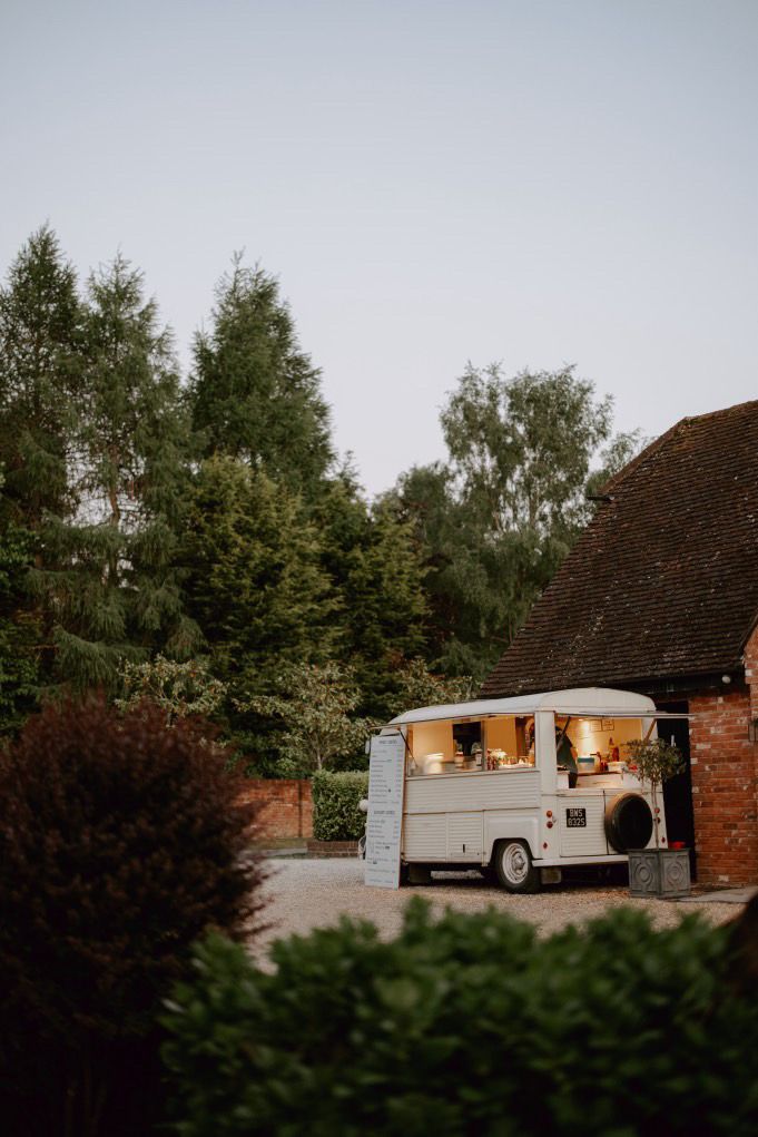 The crepe van lit up at dusk outside a venue barn