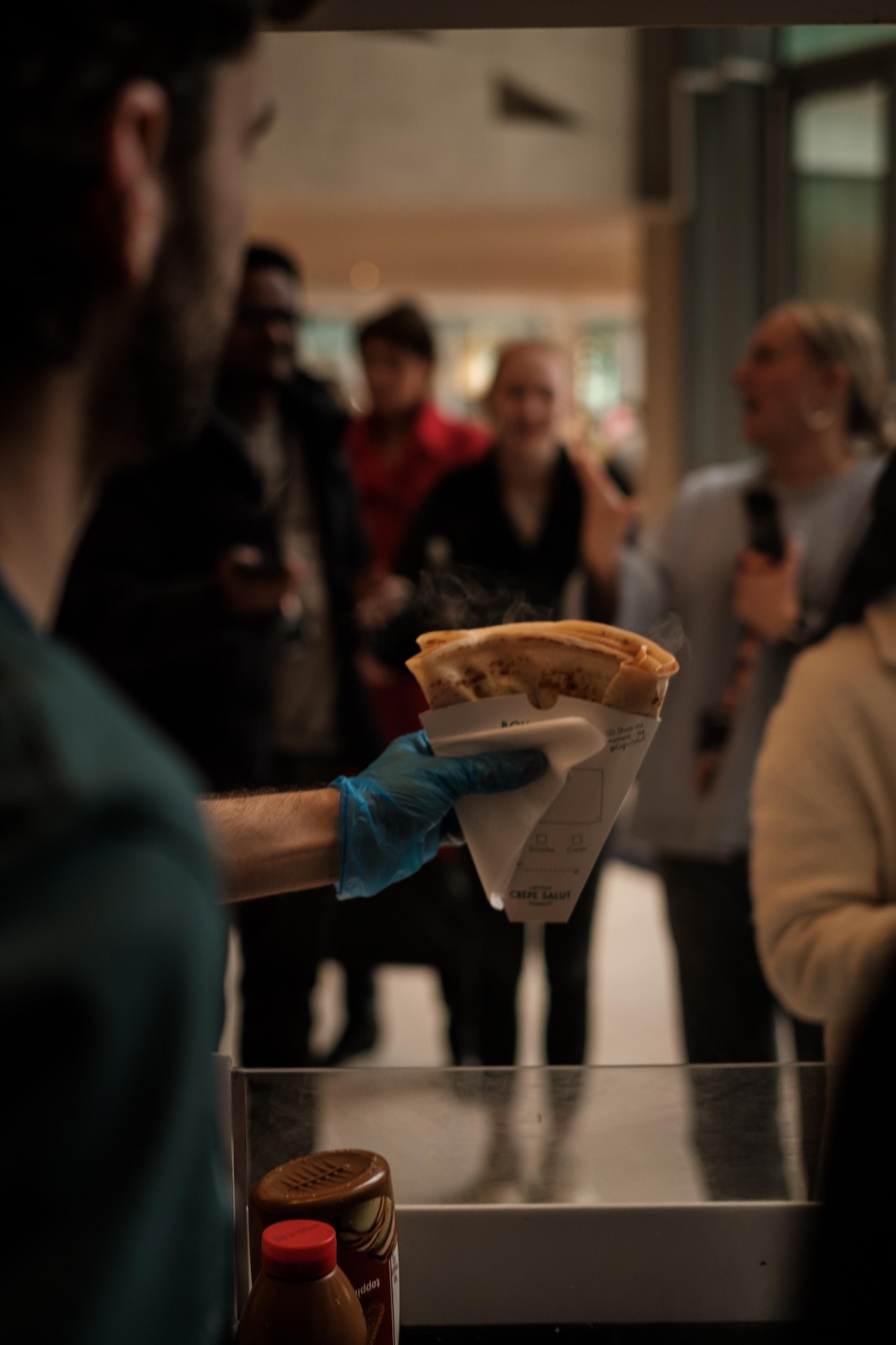 Handing a crepe to a guest at an indoor event