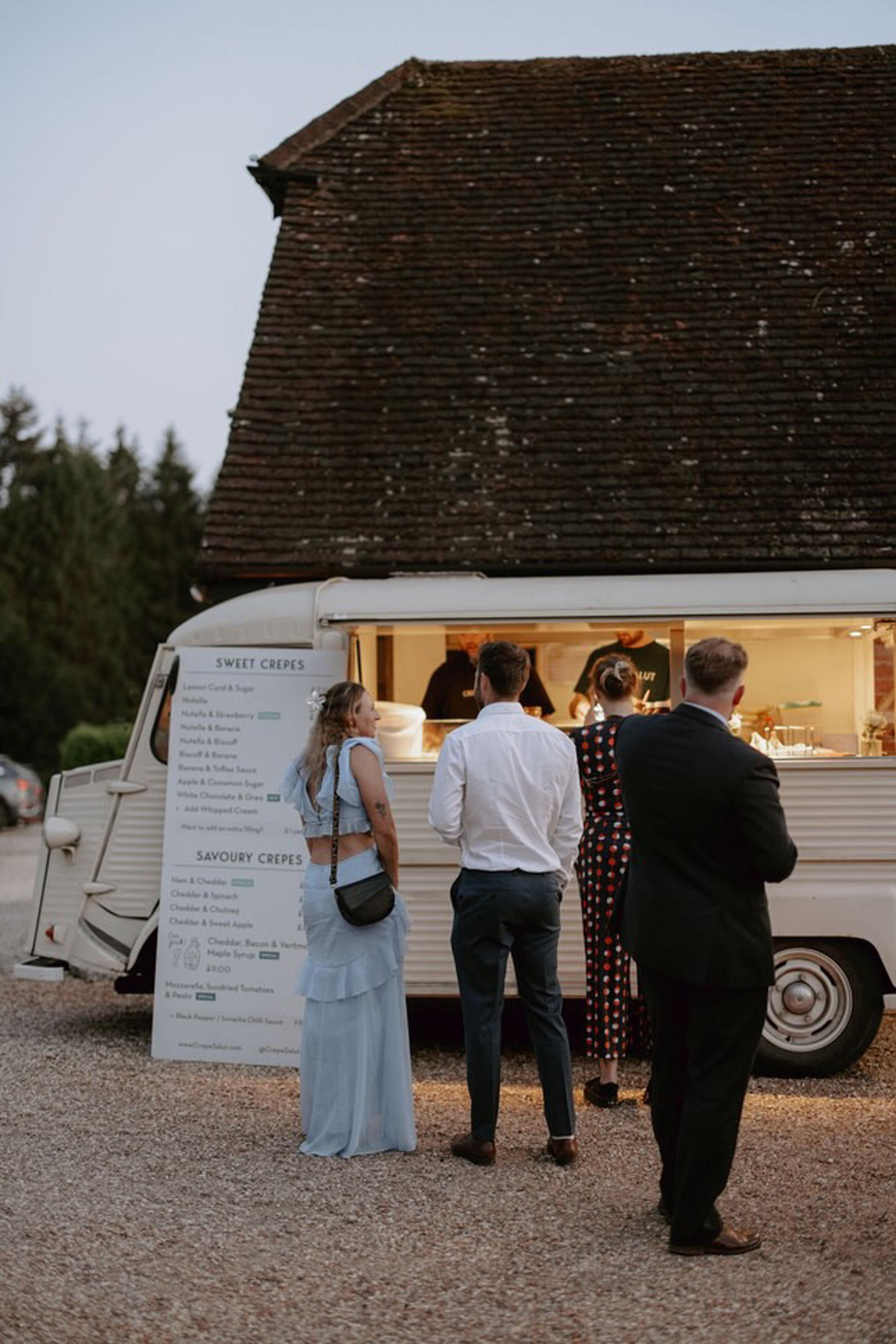 Guests ordering at the crepe van outside a barn