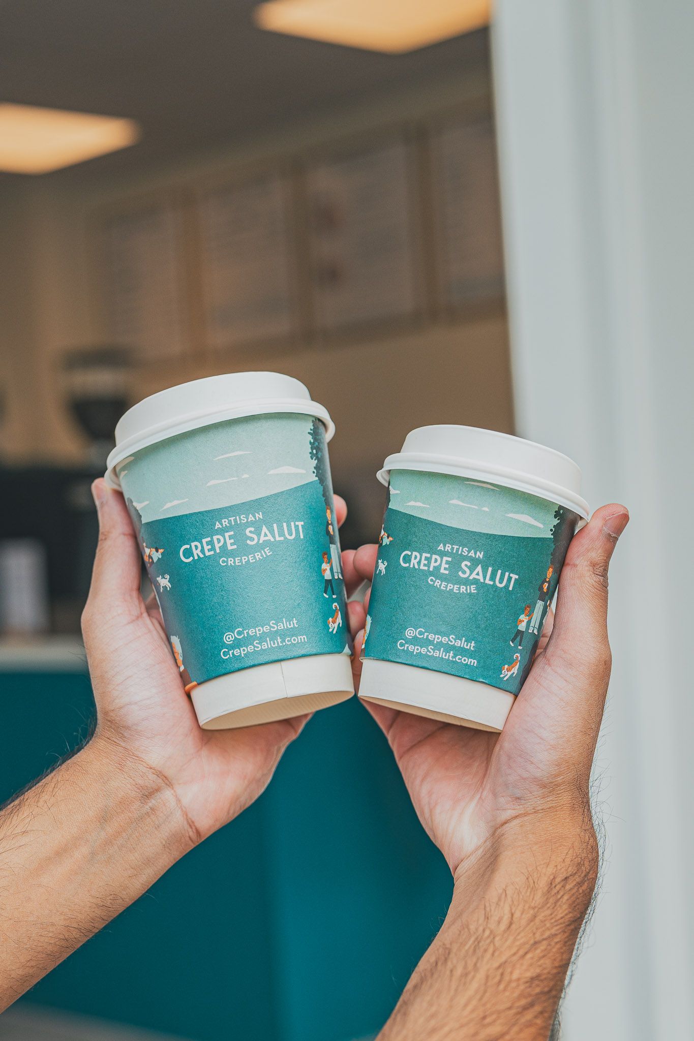 Two Crepe Salut coffee cups held up together