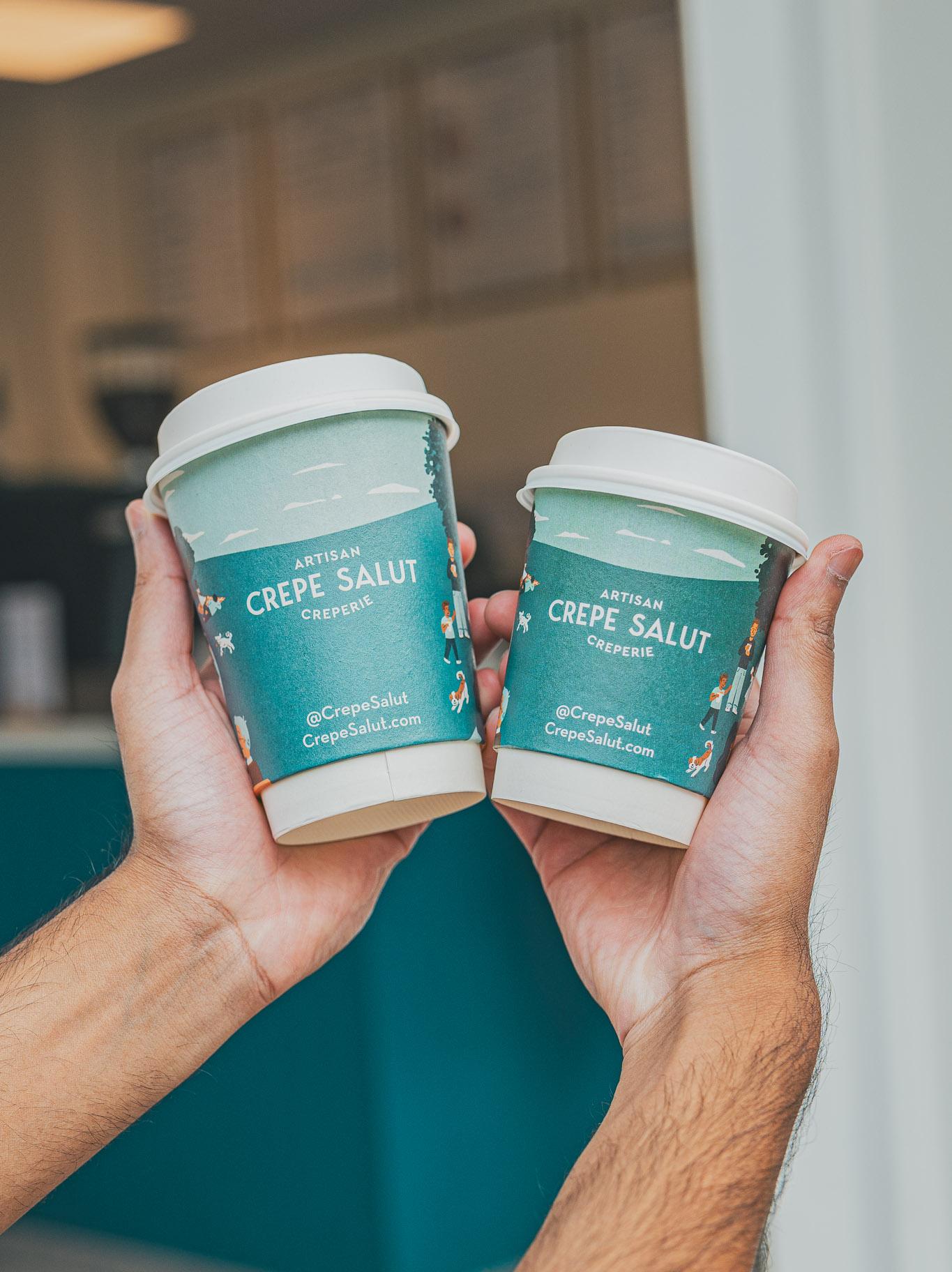 Two Crepe Salut coffee cups held up together