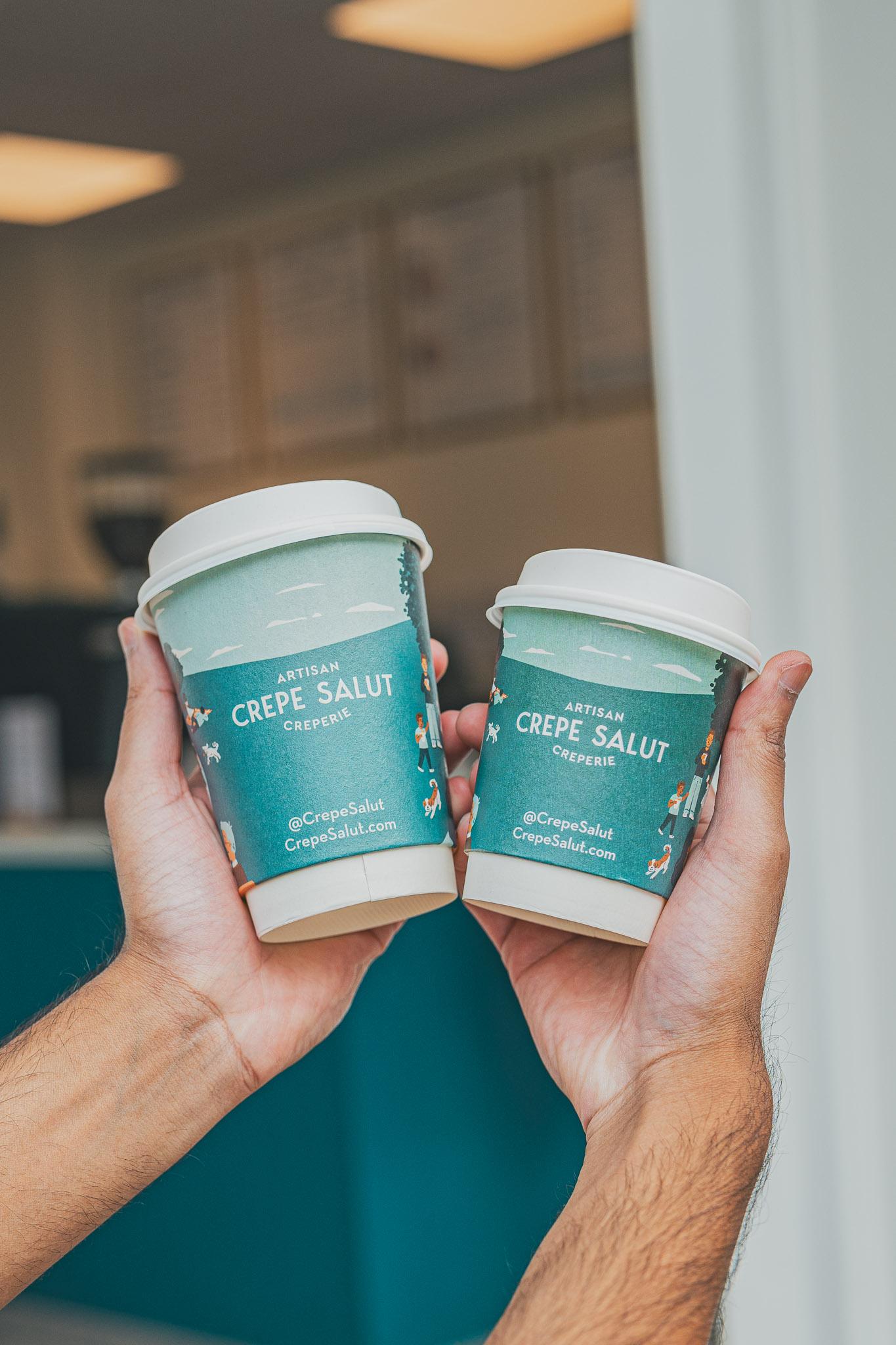 Two Crepe Salut coffee cups held up together