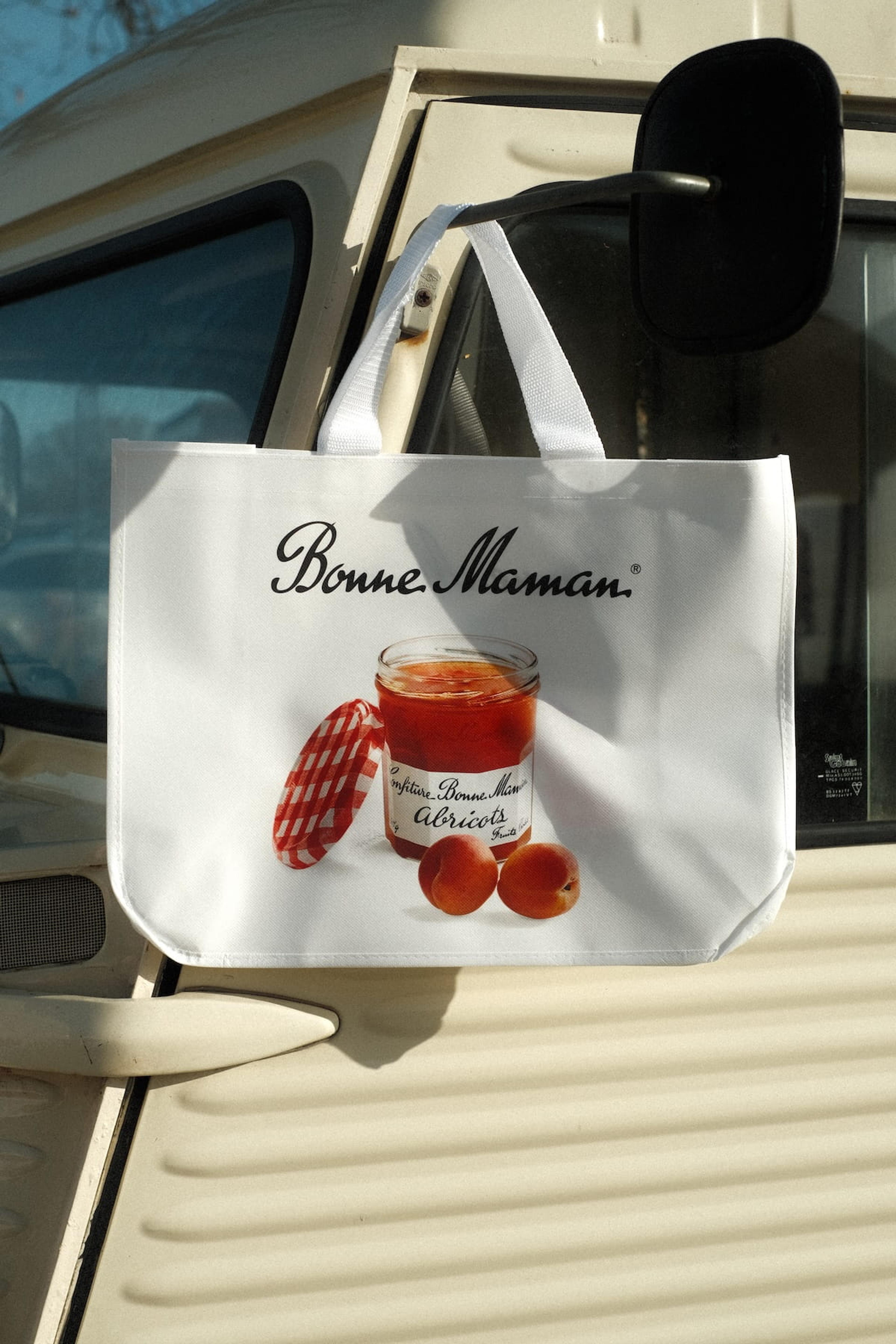 A Bonne Maman tote bag hanging from the wing mirror of the crepe van
