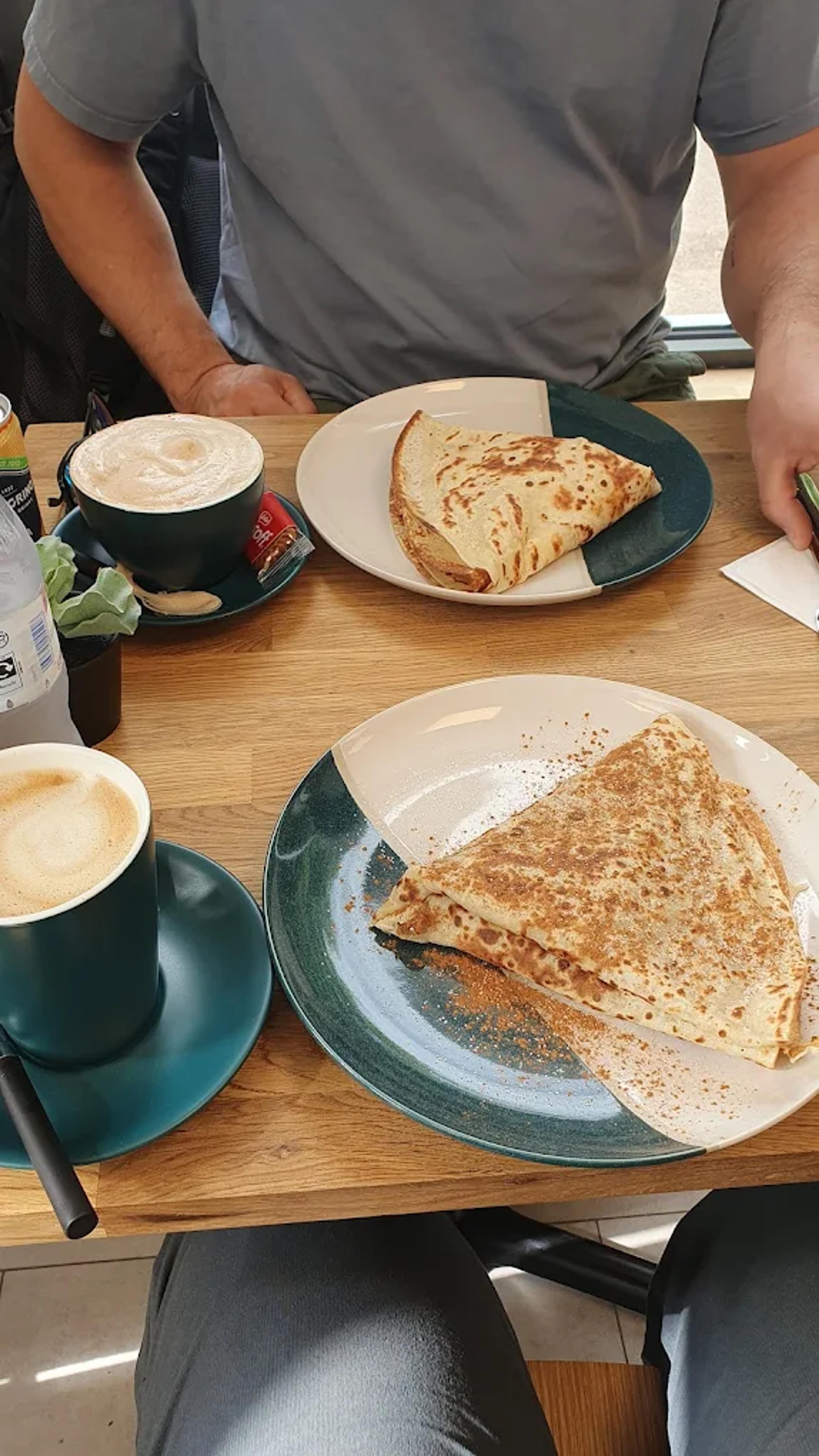 A savoury crepe and a latte on a café table
