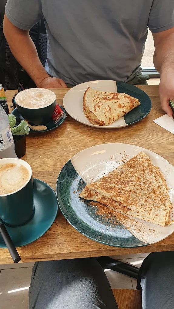 A savoury crepe and a latte on a café table