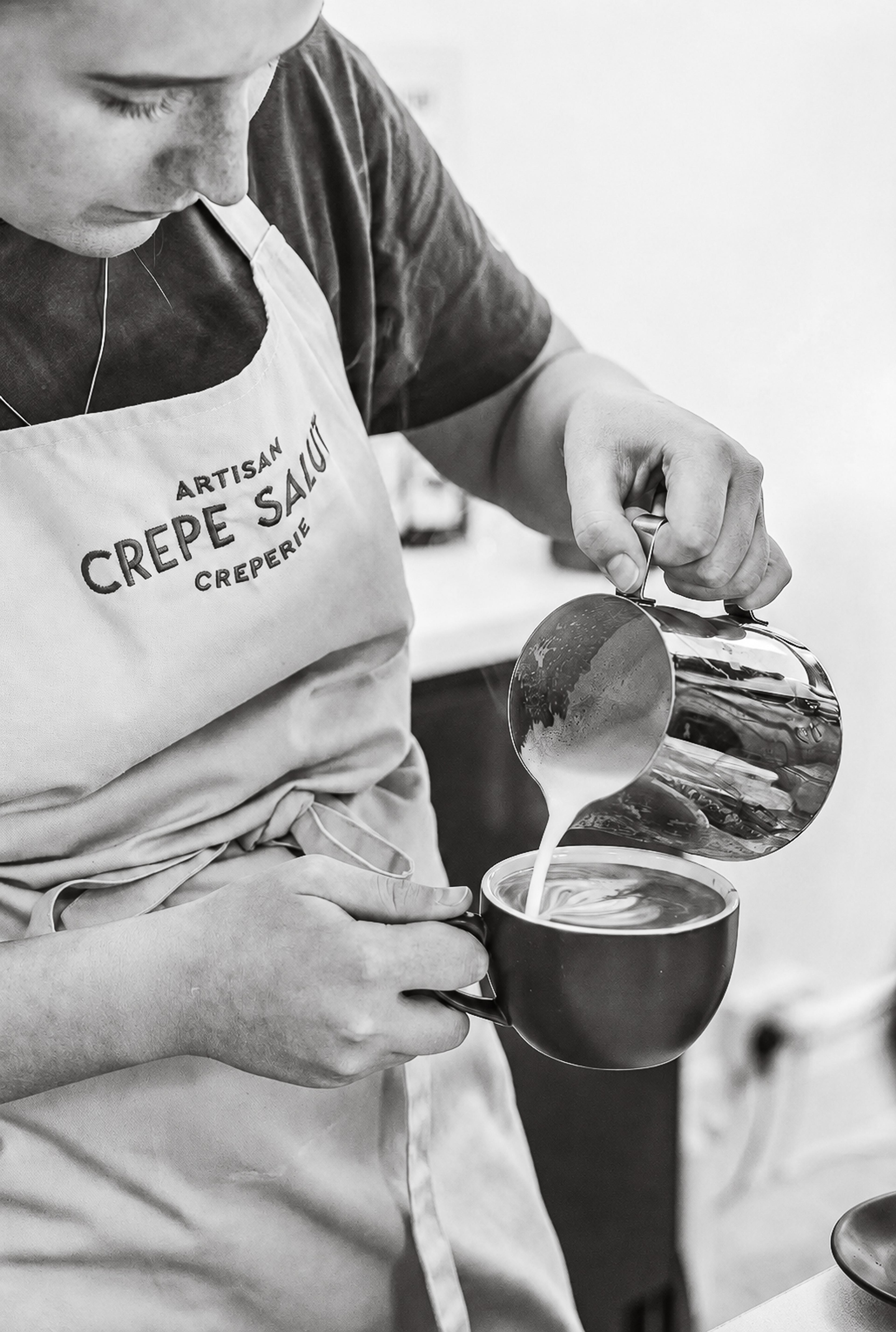 Pouring steamed milk into a coffee