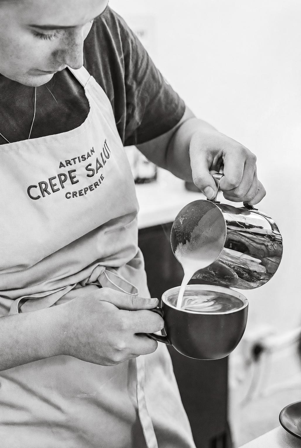 Pouring steamed milk into a coffee