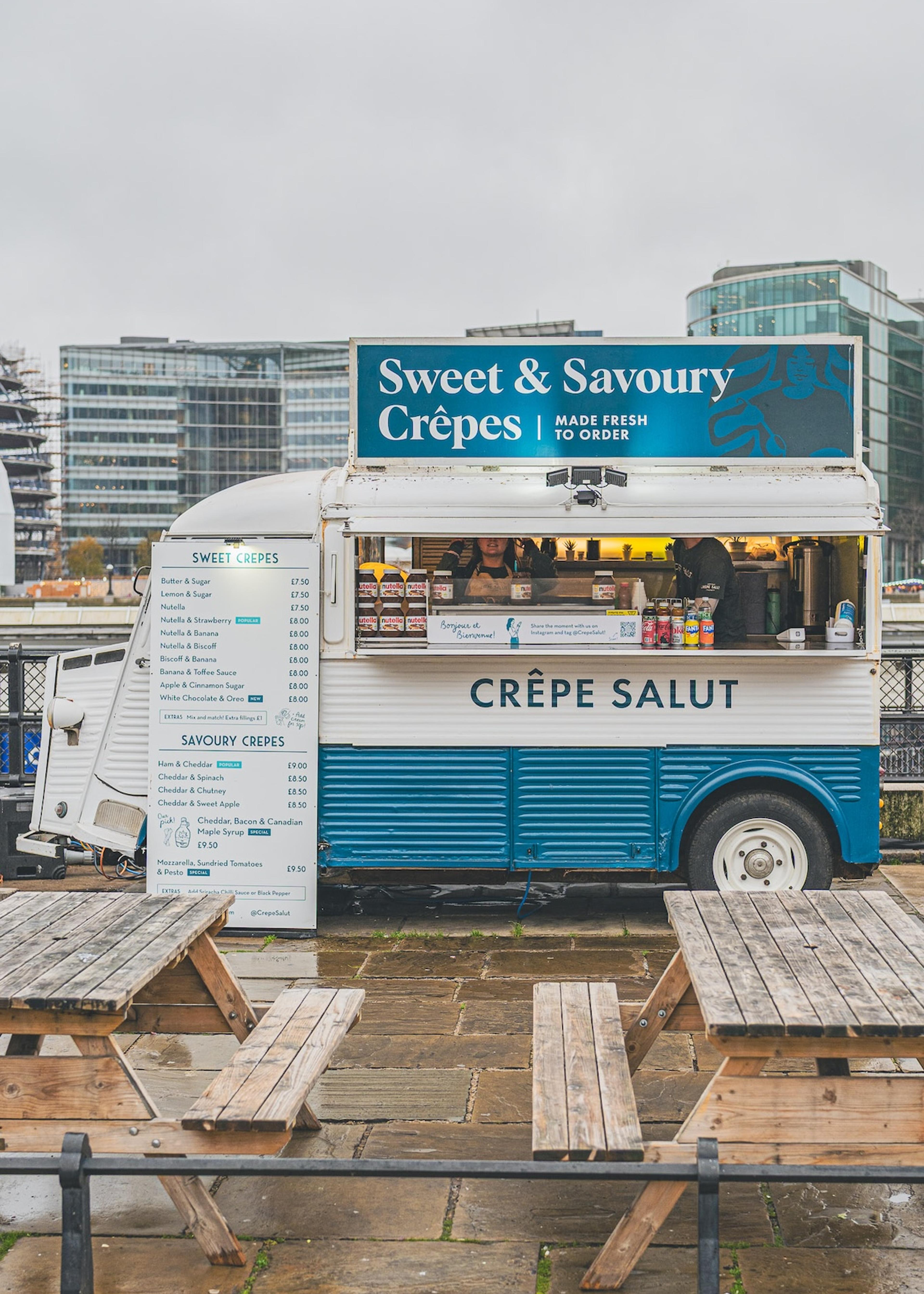 The crepe van pitched with picnic benches by the river