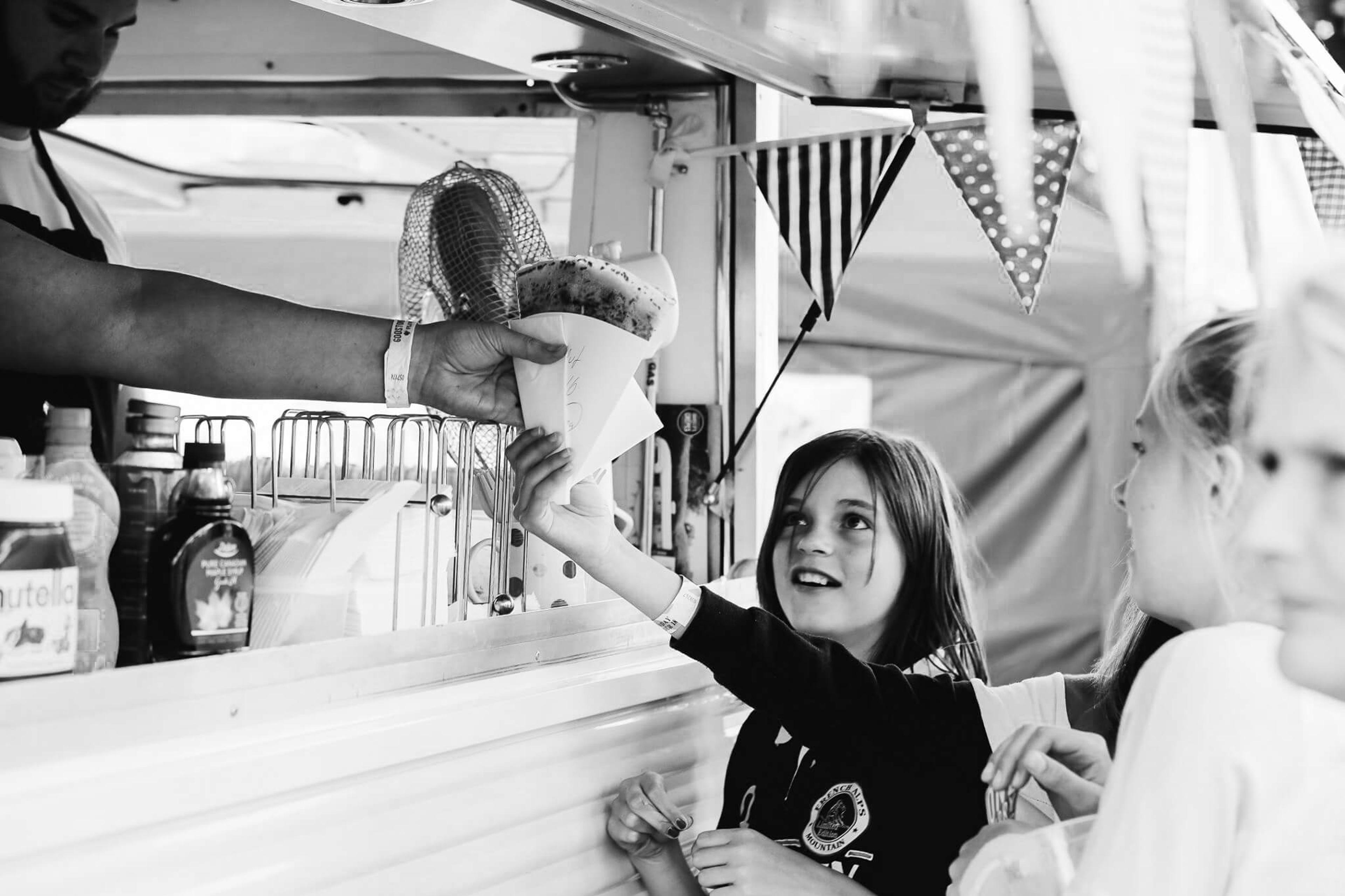 Handing a crepe to a child at a festival stall