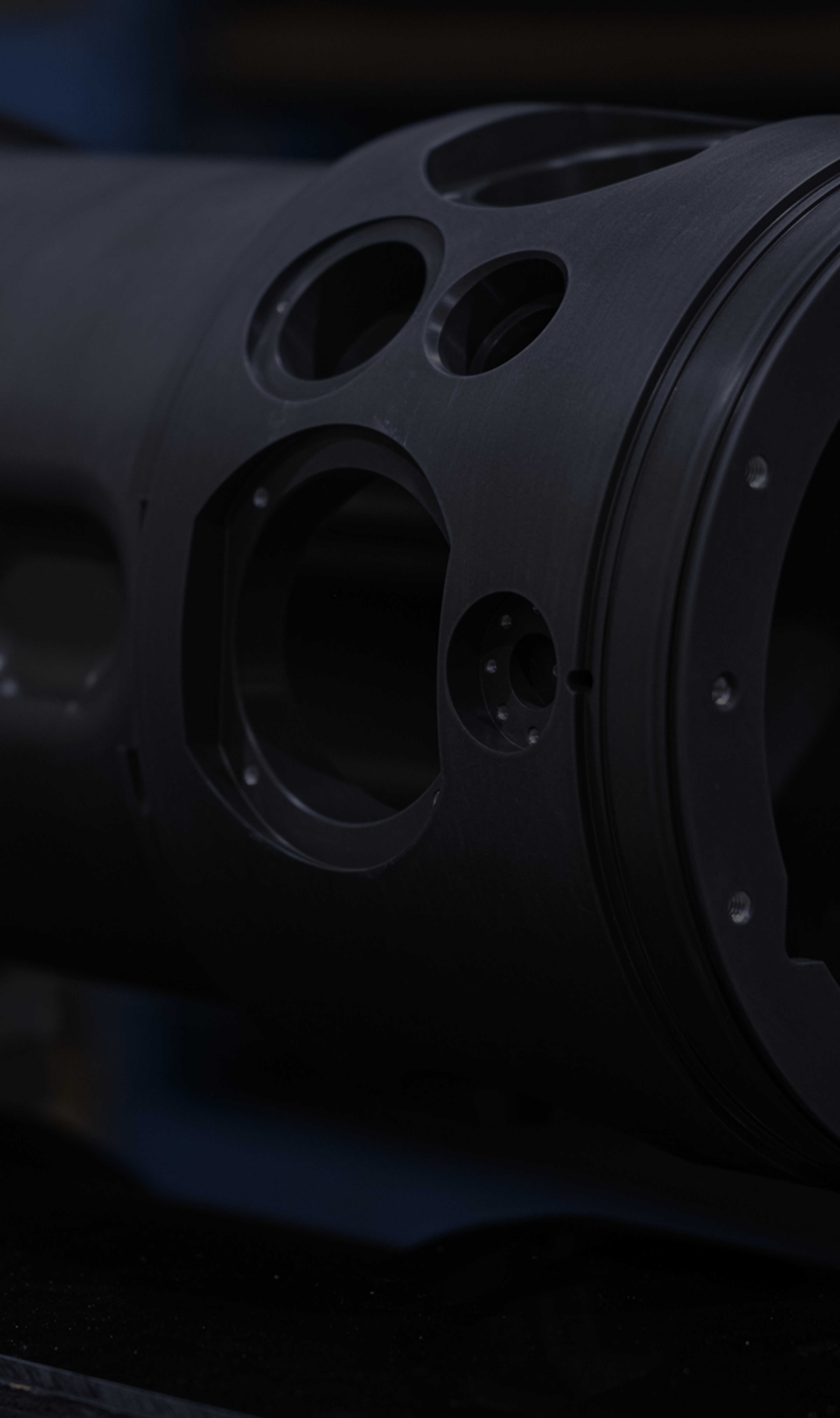 Black anodised cylindrical housing with precision-bored apertures and a flanged end