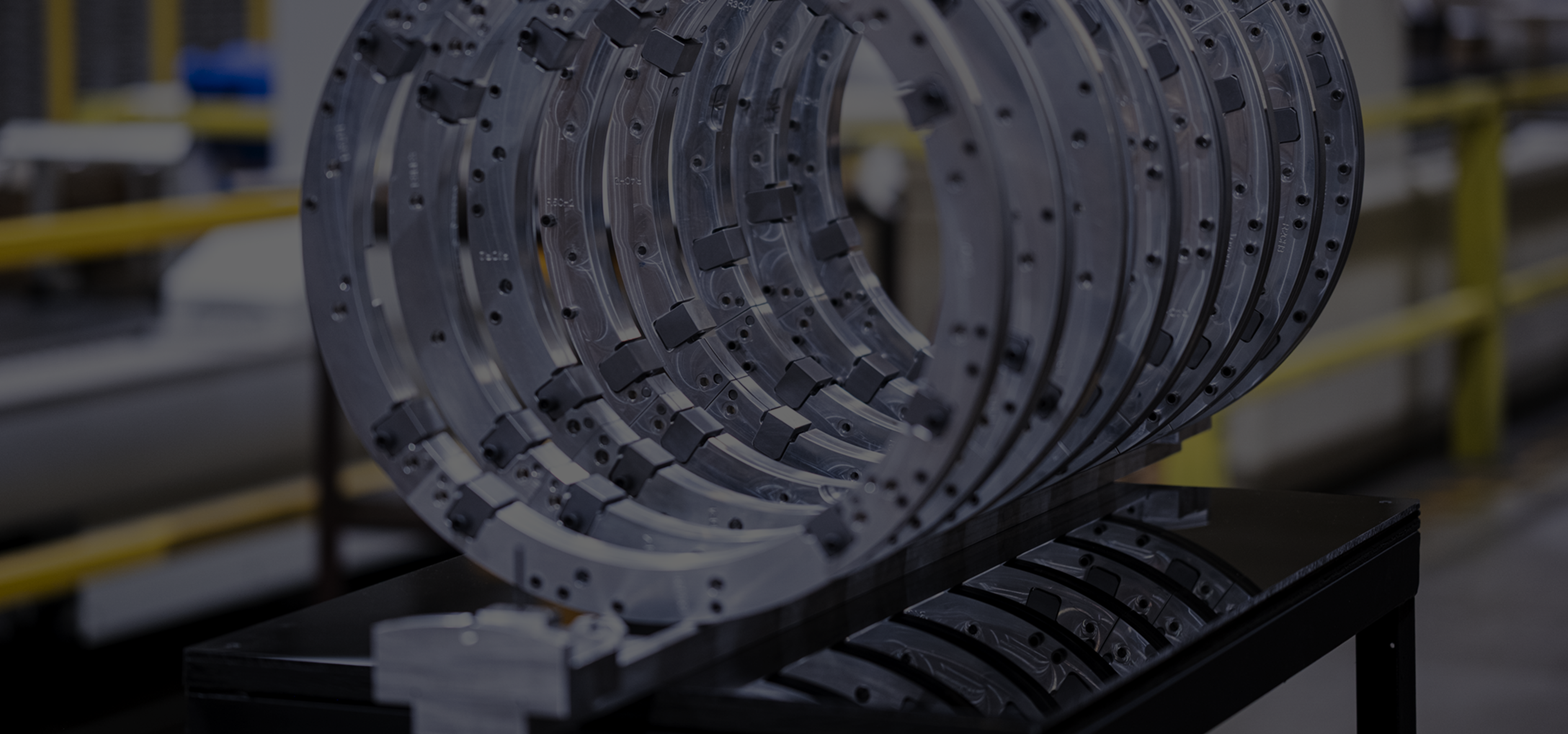 Stack of large machined ring segments staged on a shop-floor cart