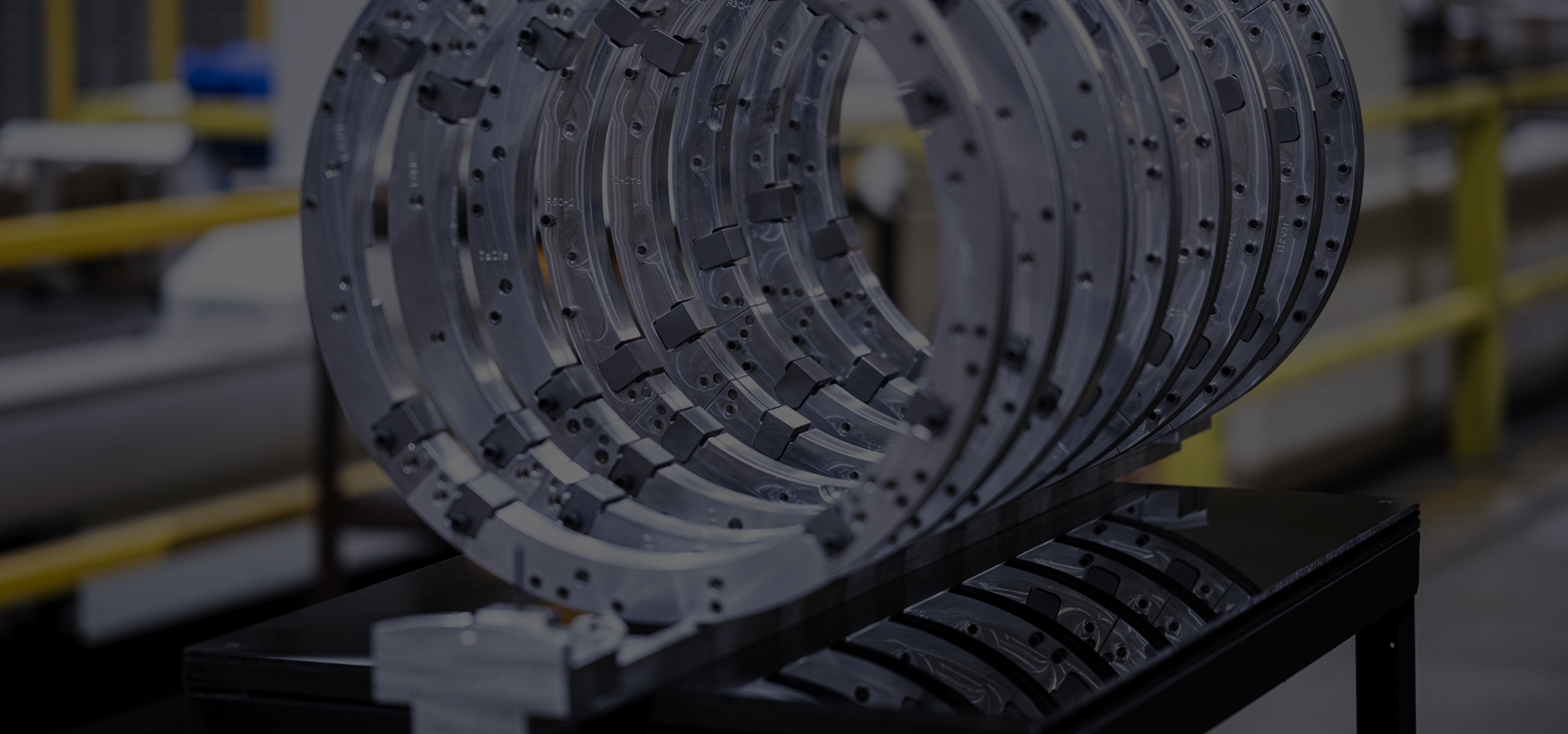 Stack of large machined ring segments staged on a shop-floor cart