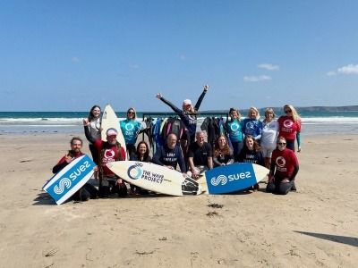 People in wetsuits and with surfboards on a beach to promote Wave Project and Suez launch if wetsuit reuse scheme in Cornwall