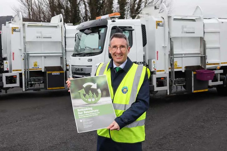 DAERA Minister Andrew Muir launches the N Ireland waste strategy document standing in front of refuse collection vehicles