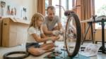 Father teaching his daughter how to repair a bike