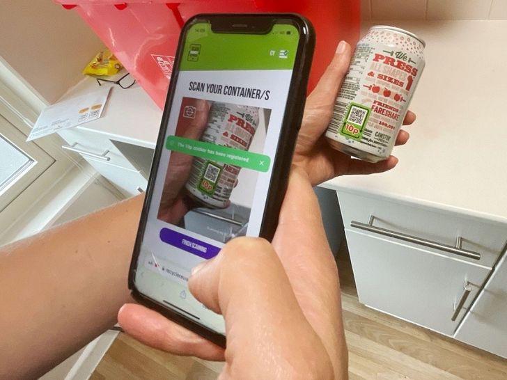 Someone scanning a QR code on side of a can in the Brecon digital deposit return scheme trial