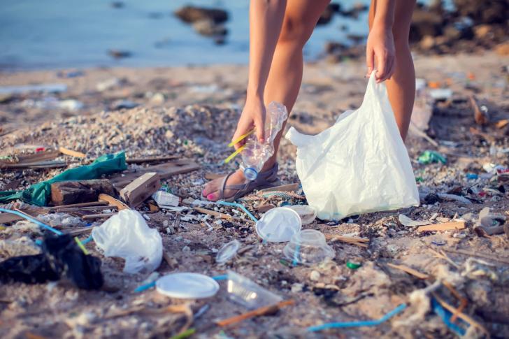 Woman's hands picking up plastic pollution on a beach