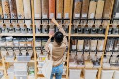Woman in a refill shop, filling a container with lentils