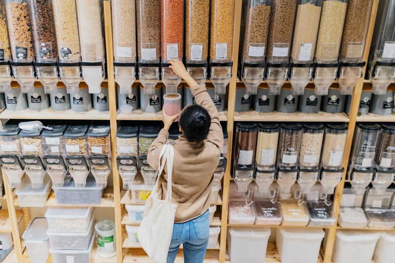 Woman in a refill shop, filling a container with lentils