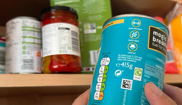 Close up of recycling labelling on side of tin in front of food cupboard