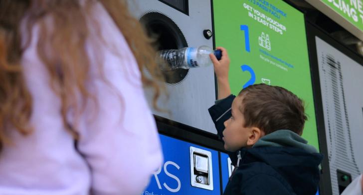 Boy putting bottle into a reverse vending machine