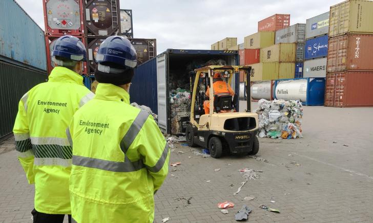Environment Agency officers watching as bales of packaging waste are unloaded by a forklift truck at a port