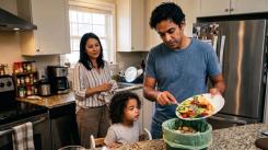 Family in a London kitchen with dad scraping food waste into a food waste caddy