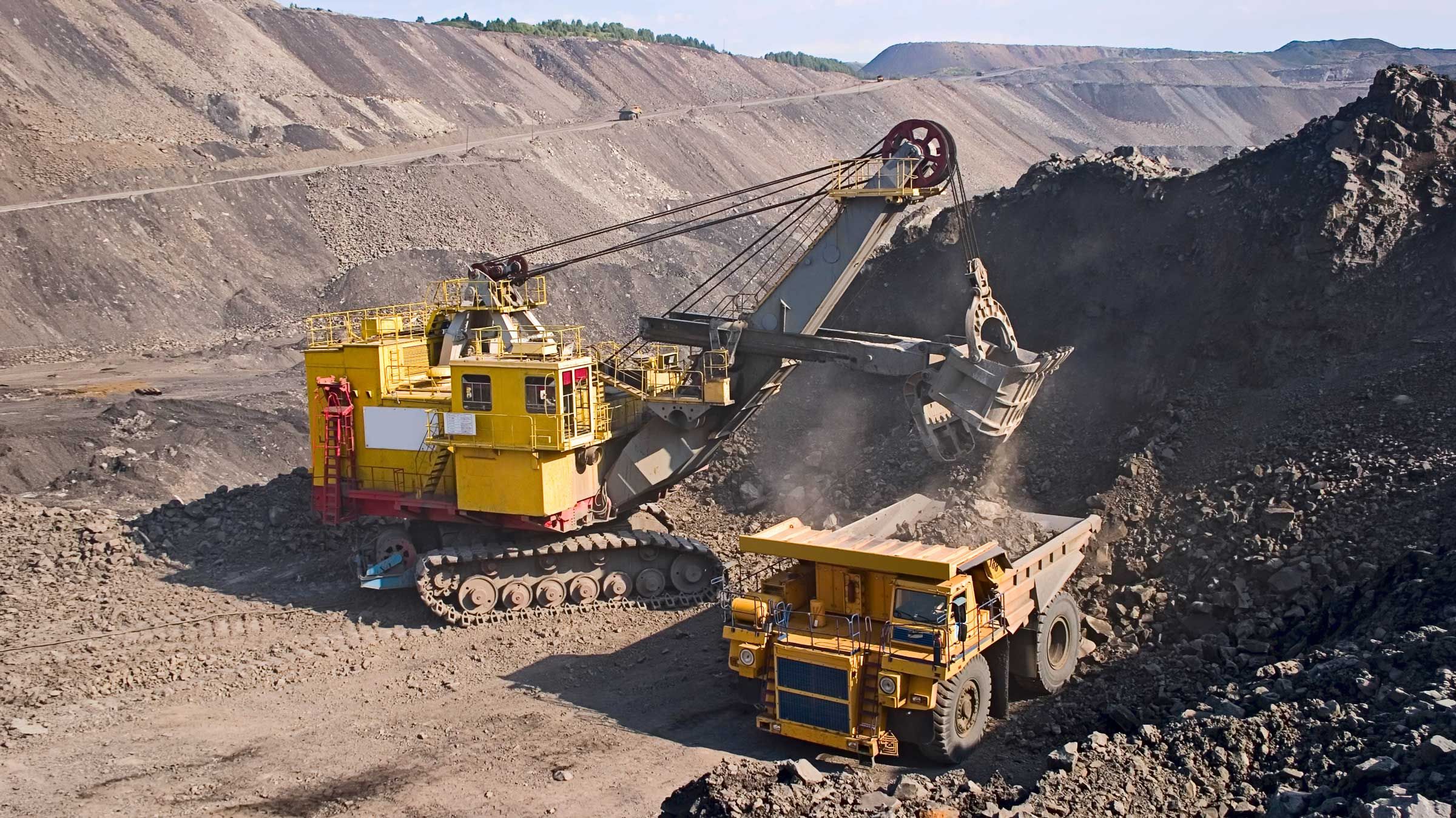 Mining vehicles loading ore at an arid mine site