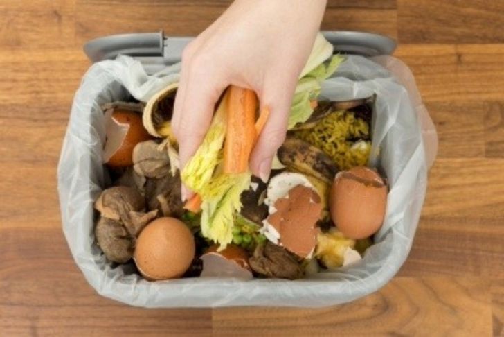 Hand holding food waste over caddy bin