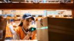 Female warehouse worker uses bar code reader while scanning packages