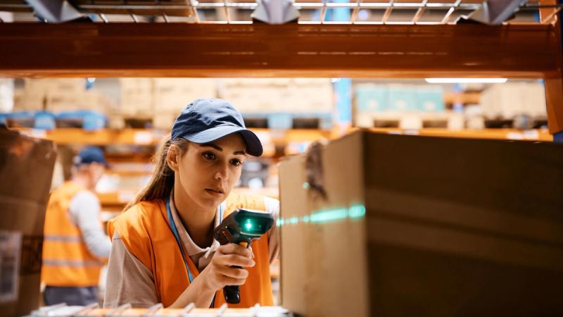 Female warehouse worker uses bar code reader while scanning packages