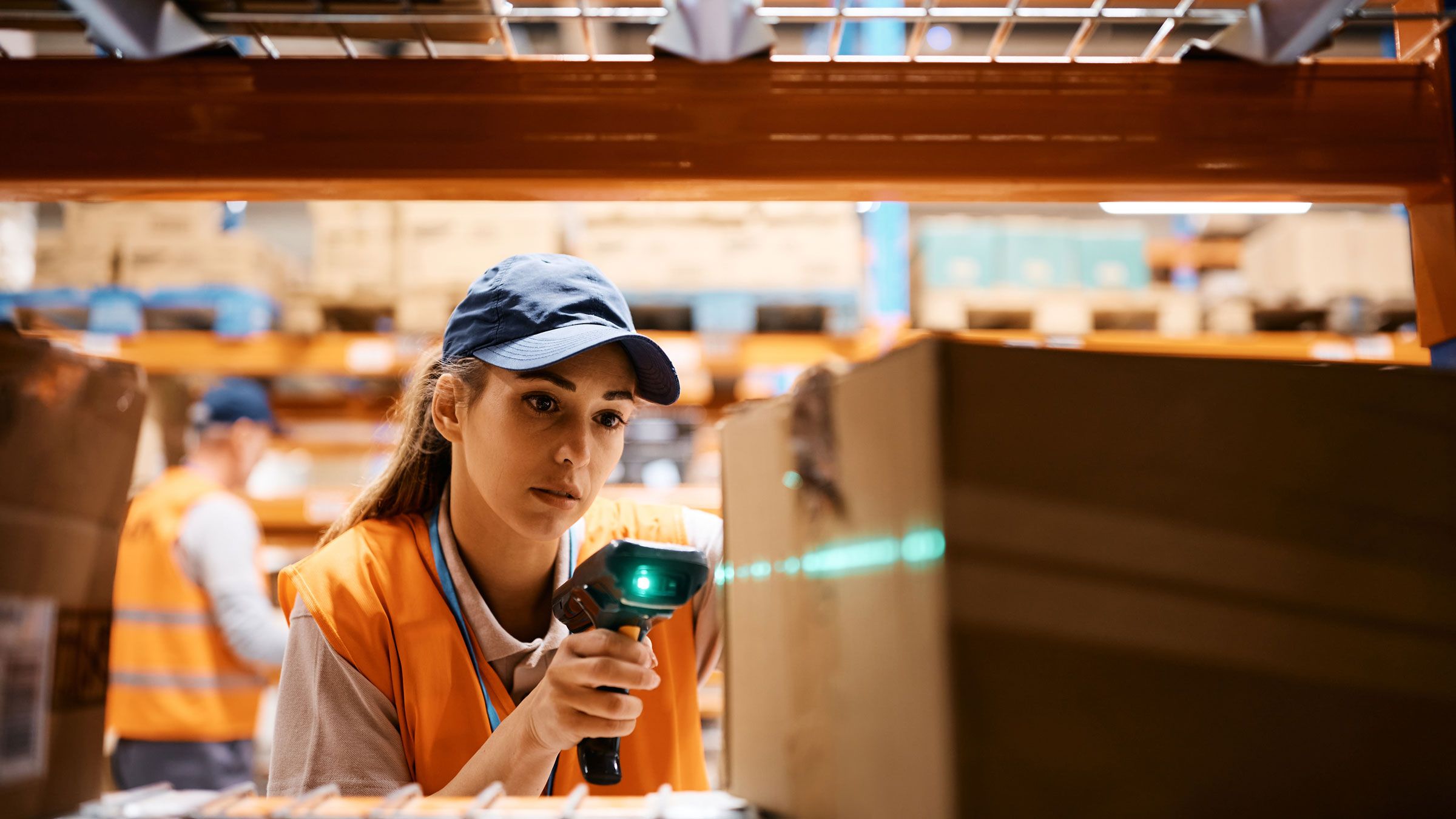Female warehouse worker uses bar code reader while scanning packages