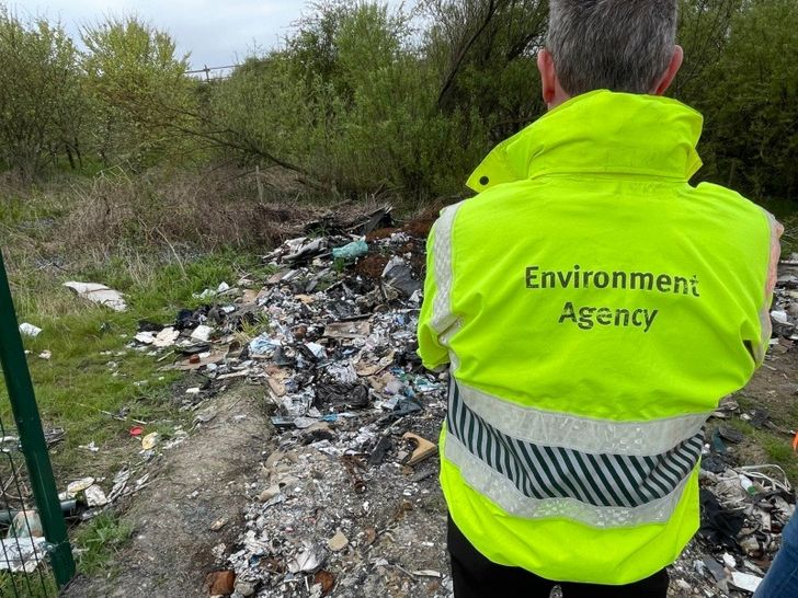 Environment Agency worker standing over waste filled plot of land