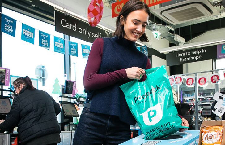 Lady in a supermarket putting a Podback bag in a return point