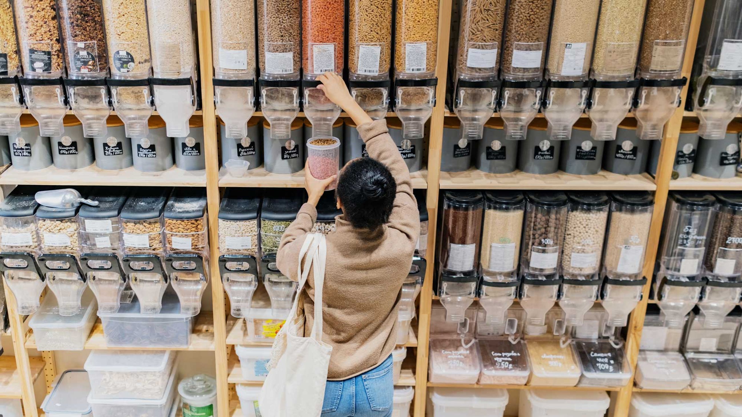 Woman in a refill shop, filling a container with lentils