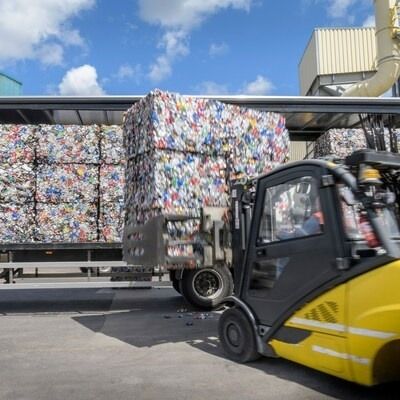 Bales of aluminium used beverage cans being unloaded by a forklift truck