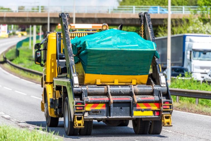 Truck carrying a waste skip on a uk motorway
