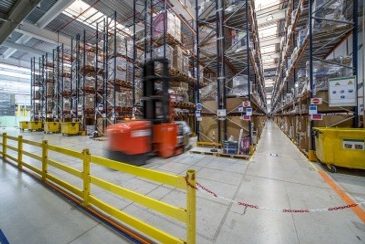 A forklift quickly moving through a warehouse