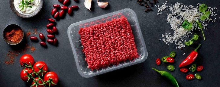Beef mince in plastic packaging, surrounded by ingredients